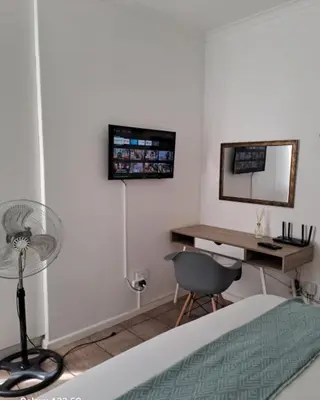 a bedroom with a desk and a fan and a bed at Azzure Apartments 4 sleeper Strand in Strand