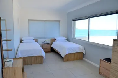 two beds in a room with a view of the ocean at Harbour View in Cape Town