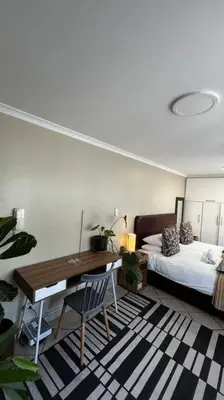 a bedroom with a desk and a bed and a desk sidx sidx sidx at Cosy Central Apartment - By ARPA Hospitalities in Stellenbosch