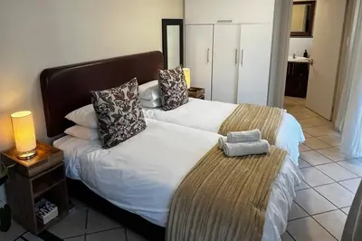a hotel room with two beds and a night stand at Cosy Central Apartment - By ARPA Hospitalities in Stellenbosch