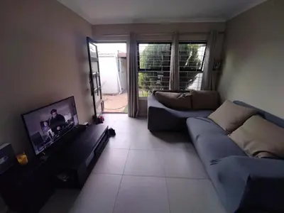 a living room with a couch and a tv at 21 Pin Oak Guest House in Cape Town