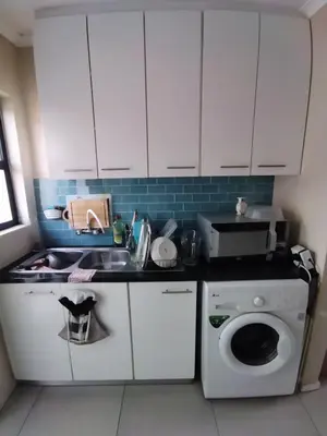 a kitchen with white cabinets and a sink and a washing machine at 21 Pin Oak Guest House in Cape Town