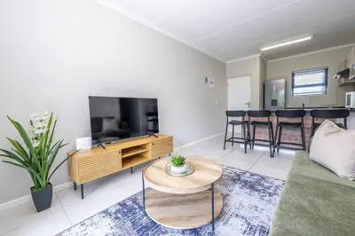 a living room with a couch and a tv and a table at Cozy Apartment in Brackenfell, Cape Town, ZA in Brackenfell