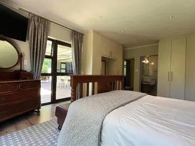 a bedroom with a bed and a dresser and a mirror at 7Pillars Villa Grenache in Durbanville