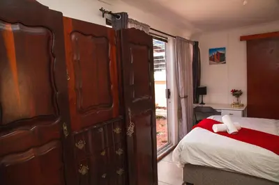 a bedroom with a bed and a large wooden wardrobe at Luxurious Flatlet in the heart of Mowbray in Cape Town