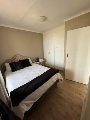 a bedroom with a large bed and a wooden floor at Hermanus Beach Club 104 in Hermanus