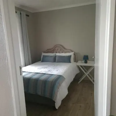 a bedroom with a bed with blue pillows and a table at Hermanus Beach Club 104 in Hermanus