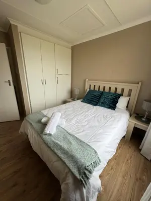 a bedroom with a large white bed with blue pillows at Hermanus Beach Club 104 in Hermanus