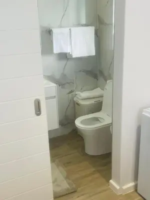 a white bathroom with a toilet and towels at Private Luxury Room by 29 Holborn in Cape Town