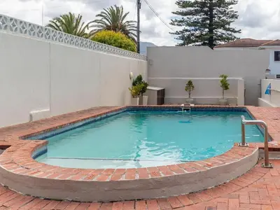 a swimming pool with a brick walkway around it at Hermanus - Heart of the Sea in Hermanus