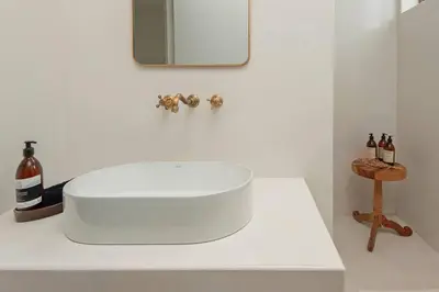 a white sink in a bathroom with a mirror at Heartwood Cottage in Hermanus