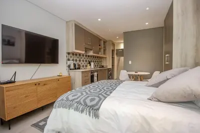 a bedroom with a large bed and a kitchen at 23 On The Den Studio Apartment in Stellenbosch