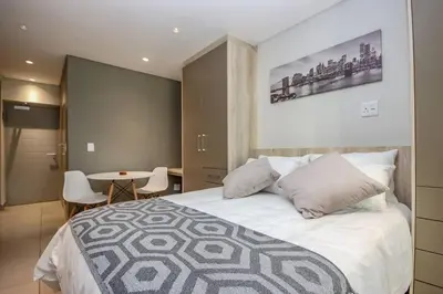 a bedroom with a large bed and a table at 23 On The Den Studio Apartment in Stellenbosch