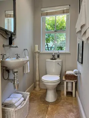 a bathroom with a toilet and a sink and a window at Sandpipers in Hermanus