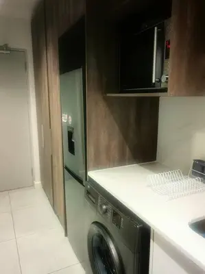 a kitchen with a washing machine and a microwave at Ocean Palace Table View in Cape Town