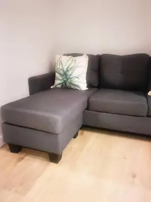 a black couch with a pillow on a wooden floor at Ocean Palace Table View in Cape Town
