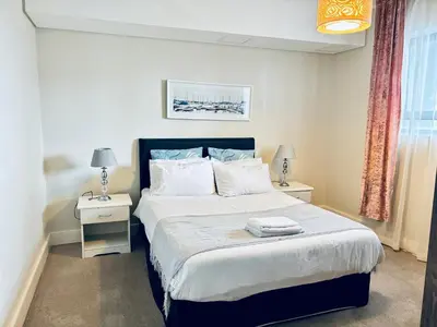 a bedroom with a large bed with two night stands at 6 sleeper apartment near Canal Walk in Cape Town