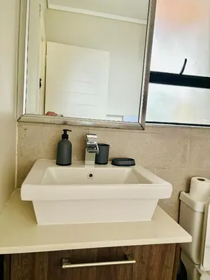 a white sink in a bathroom with a mirror at 6 sleeper apartment near Canal Walk in Cape Town