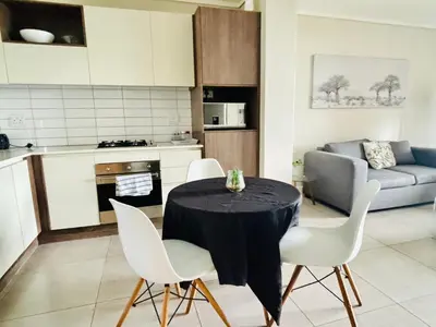a kitchen with a table and chairs in a room at 6 sleeper apartment near Canal Walk in Cape Town