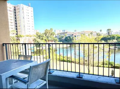 a balcony with a table and a view of the water at 6 sleeper apartment near Canal Walk in Cape Town