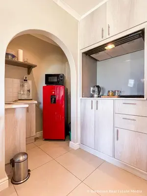 a red refrigerator in a kitchen with white cabinets at 7Pillars Shiraz in Durbanville