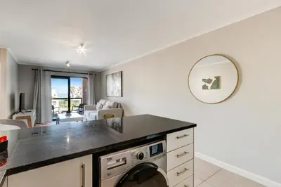 a kitchen with a washer and dryer in a room at Beachside Getaway in Cape Town