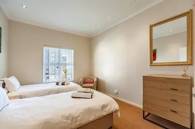 a bedroom with two beds and a mirror at Coral Breeze Walk to Everything in Cape Town