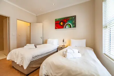 two beds in a room with a painting on the wall at Coral Breeze Walk to Everything in Cape Town