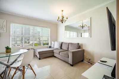 a living room with a couch and a table at Coral Breeze Walk to Everything in Cape Town