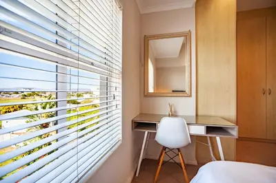 a bedroom with a window with blinds at Coral Breeze Walk to Everything in Cape Town