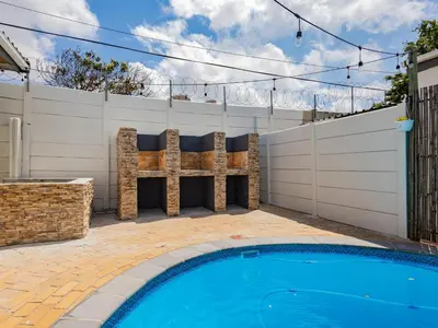 a swimming pool in front of a fence at La Bella Vida Self Catering Apartments in Bellville