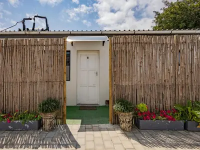 a wooden fence with a white door and some plants at La Bella Vida Self Catering Apartments in Bellville