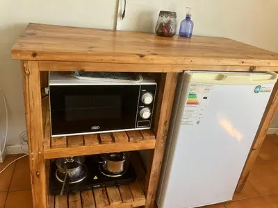 a microwave in a wooden stand next to a refrigerator at Table View Lodge in Cape Town