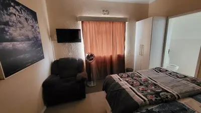 a bedroom with a bed and a chair next to a window at The Vasco in Cape Town