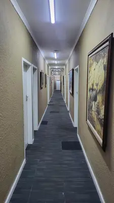 a long hallway with paintings on the walls at The Vasco in Cape Town