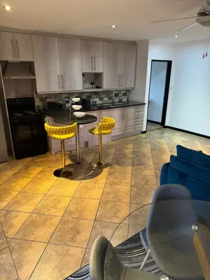 a kitchen with yellow chairs and a table and a couch at Shalom in Cape Town