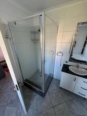a bathroom with a glass shower and a sink at Shalom in Cape Town