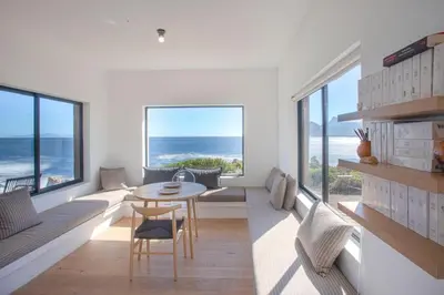 a living room with a table and some windows at Villa Sur La Mer in Pringle Bay