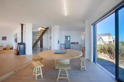 a dining room and living room with a table and chairs at Villa Sur La Mer in Pringle Bay
