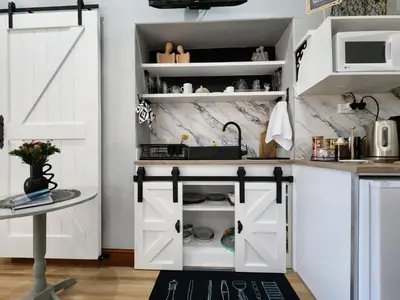 a kitchen with white cabinets and white appliances at Le Graan Guestroom in Malmesbury