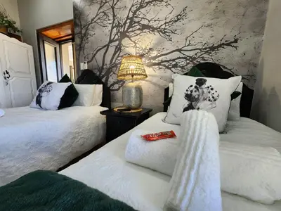 a bedroom with two beds and a lamp on a table at Le Graan Guestroom in Malmesbury