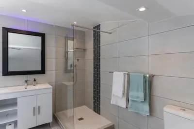 a bathroom with a shower and a sink and a mirror at 34 Gordonia, Beachfront Penthouse in Gordonʼs Bay