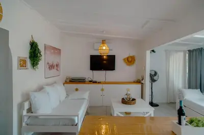 a living room with a white couch and a tv at The Ocean Side Cottage in Cape Town