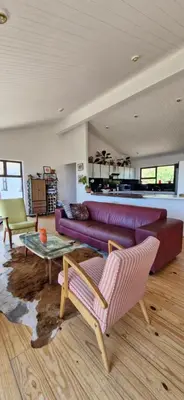a living room with a purple couch and a table at Paradise 'tween sea and mountain in Pringle Bay