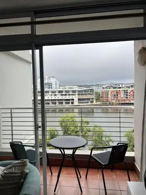 a table and chairs in front of a large window at Tyger waterfront apartment in Cape Town