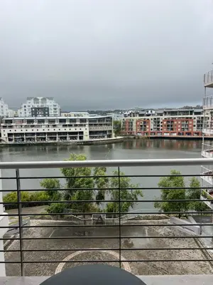 a balcony with a view of a river and buildings at Tyger waterfront apartment in Cape Town