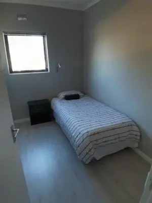 a small bedroom with a bed with a window at Astros Lodge in Cape Town