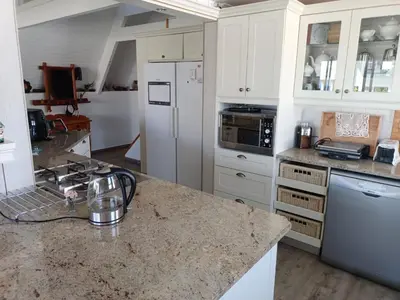 a kitchen with white cabinets and a granite counter top at Scenic Bliss Holiday Home in Kleinmond