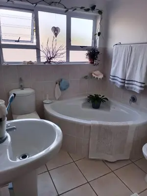 a bathroom with a tub and a toilet and a sink at Scenic Bliss Holiday Home in Kleinmond