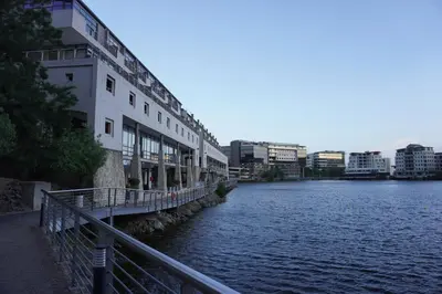 a bridge over a river next to a building at Tyger Lake Luxury Loft in Cape Town